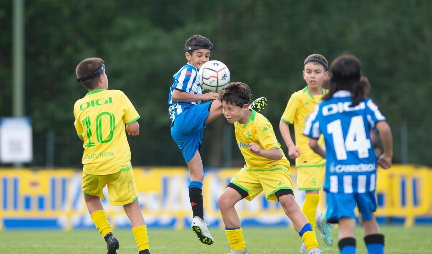 Niños entrenando fútbol mientras usan un cinta protectora para la cabeza 