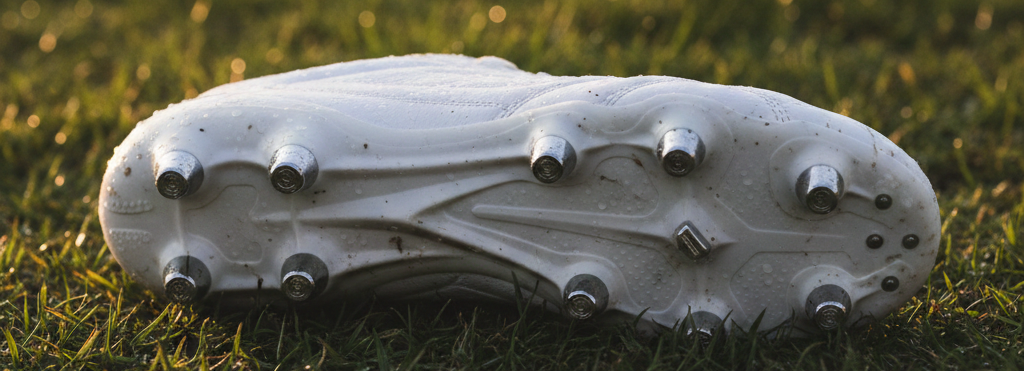 Botas de fútbol para césped natural húmedo o embarrado con tacos SG metálicos y de goma.