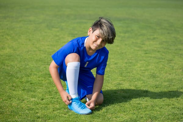 Niño atandose la botas antes de realizar un ejercicio de posesión para fútbol